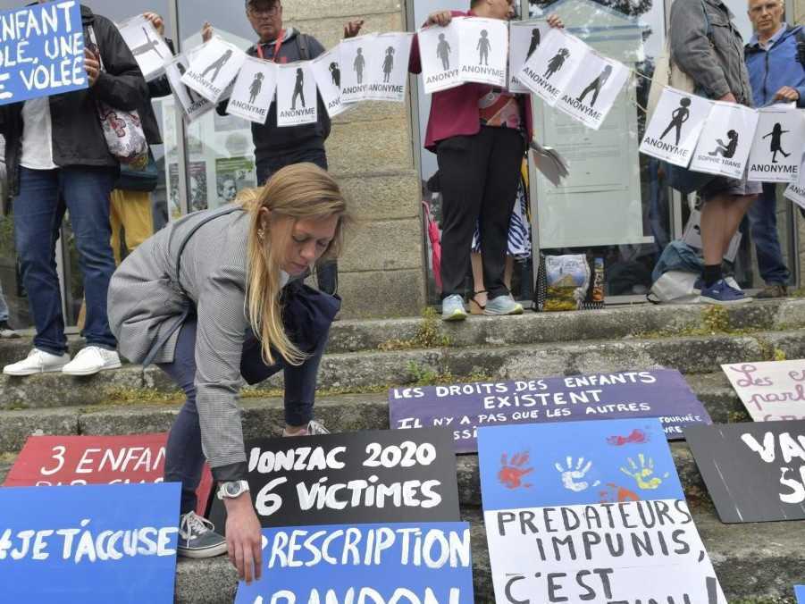 Ľudia umiestňujú plagáty počas demonštrácie pred vynesením rozsudku v procese so 74-ročným bývalým chirurgom.