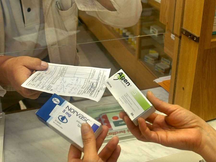 Na snímke zákazníčka v lekárni ukazuje recept a lieky na predpis lekárnikovi.