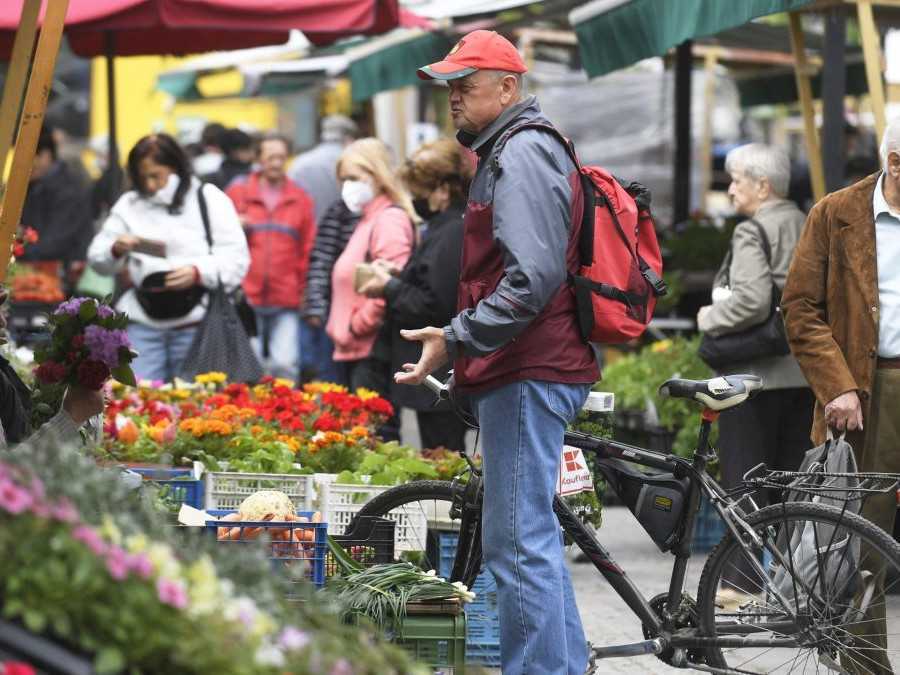 Muž na trhu konverzuje so ženou, ktorá predáva kvety.