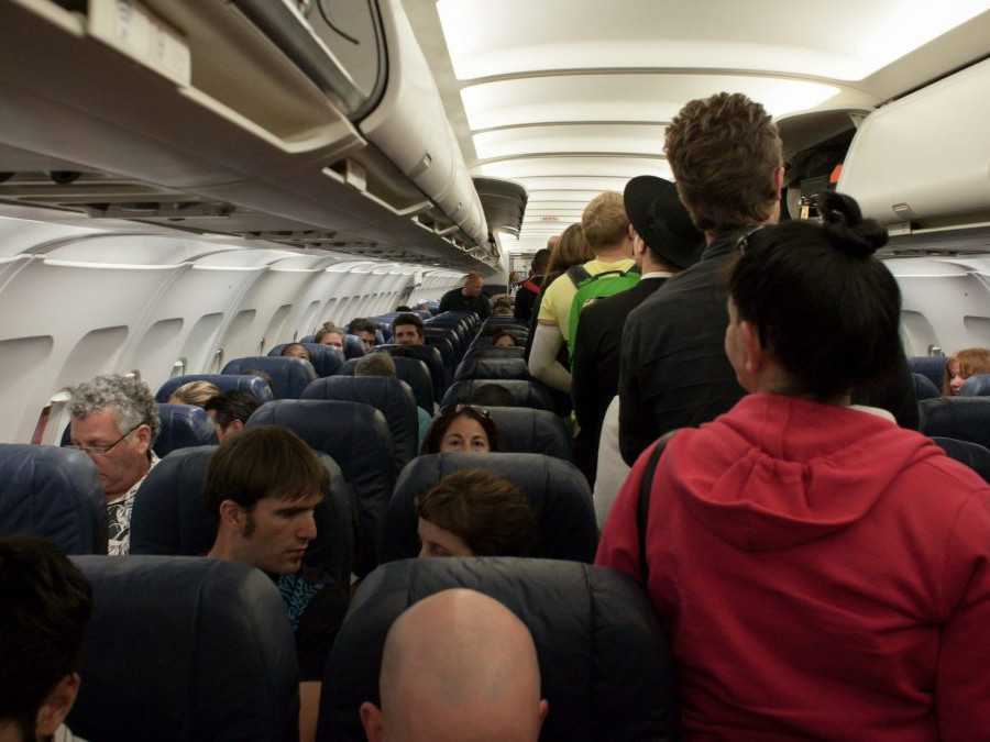 Na snímke sú pasažieri, ktorí stoja v uličke lietadla.