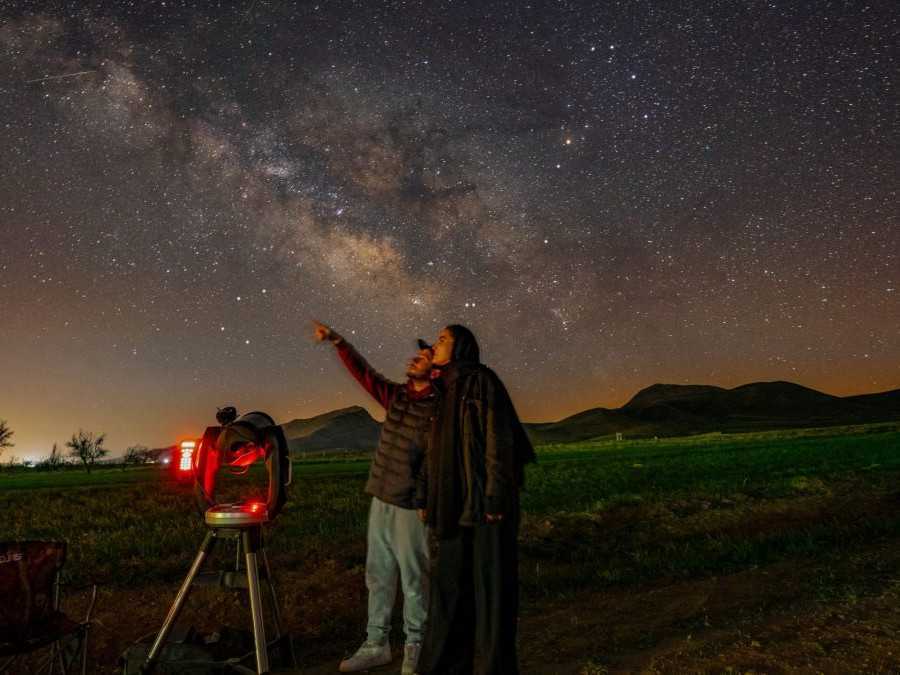 Muž a žena pozorujú hvizdy pomocou teleskopu.