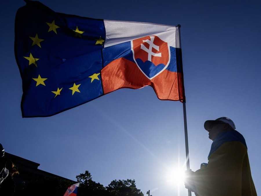 Na ilustračnej snímke osoba drží vlajky Slovenska a EÚ.