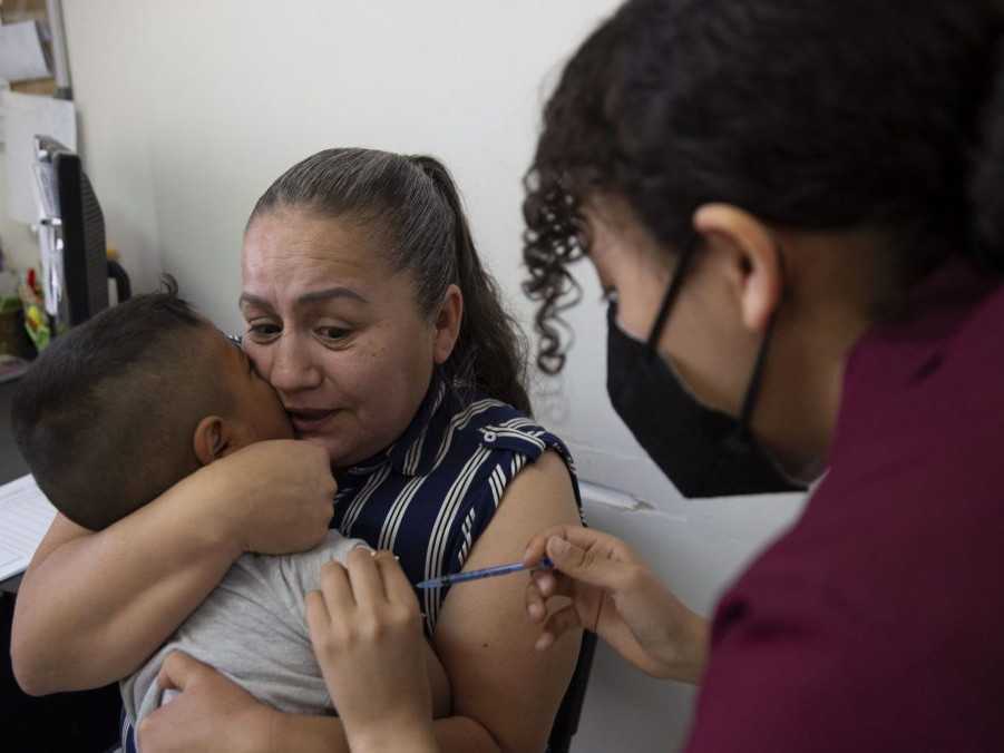 matka drží dieťa, kým ho očkujú proti osýpkam