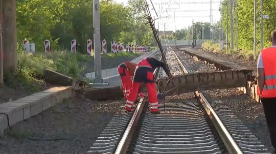 Technici odstraňujú úlomky mosta zo železničnej trati.