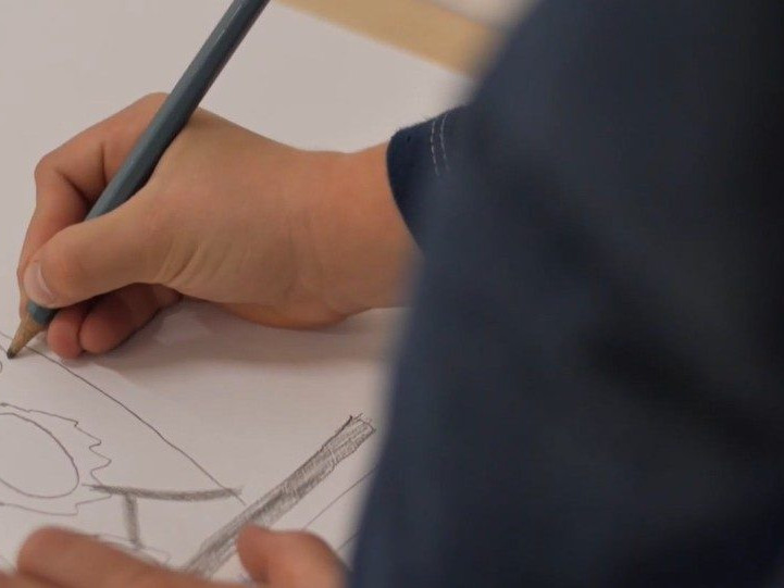 Na snímke dieťa kreslí ceruzou obrázok.