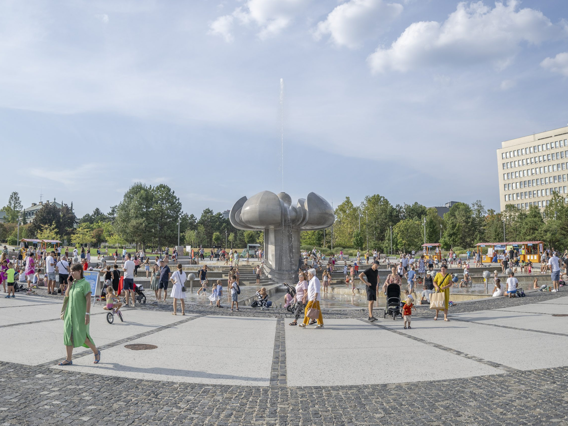 Na archívnej snímke ľudia sa ochladzujú vo fontáne počas horúčav na Námestí slobody v Bratislave.