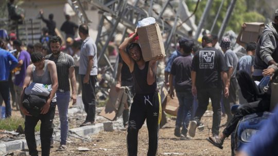 Palestínčania nesú krabice a tašky s humanitárnou pomocou.