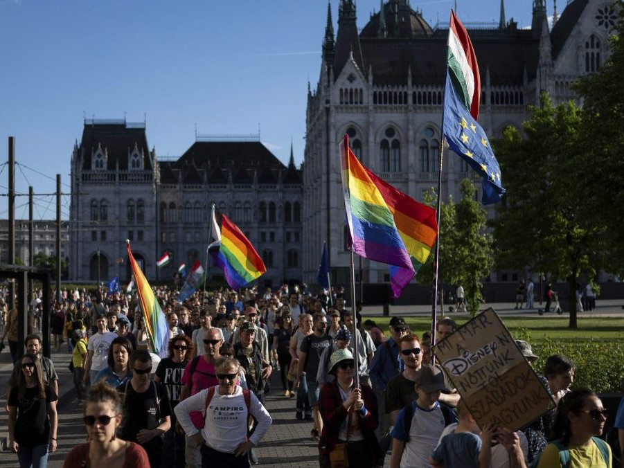 Pochod proti zákazu LGBT+ podujatí v centre Budapešti, ľudia mávajú dúhovými vlajkami.