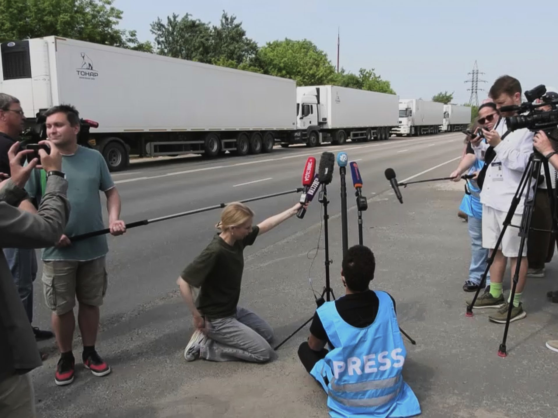 Novinári neďaleko konvoja, ktorý sa pripravuje na prevoz tiel padlých vojakov.