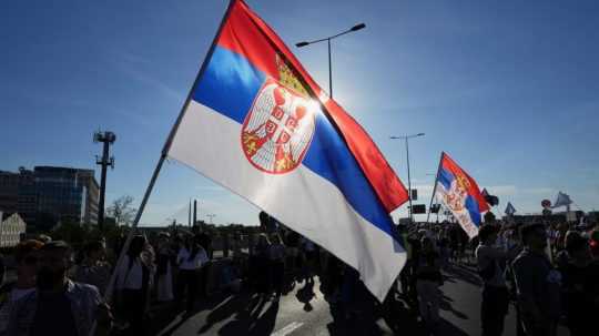 Protestujúci so srbskou vlajkou.