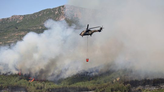Na snímke vrtuľník zhadzuje vodu počas hasenia lesného požiaru v Seferihisare neďaleko Izmiru na juhozápade Turecka.