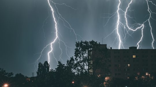 Na snímke sú blesky nad kopcami a lesom.