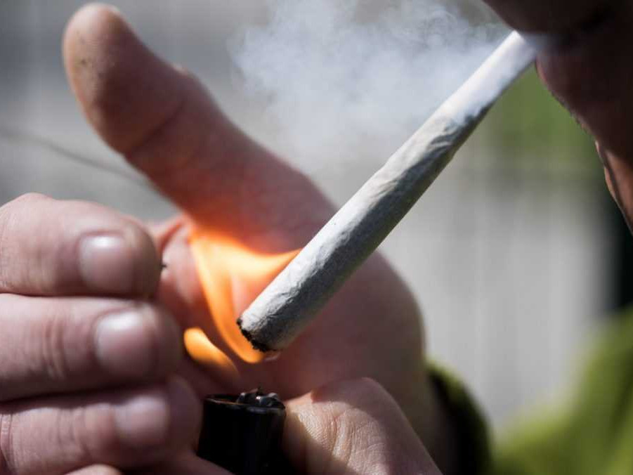 Na ilustračnej snímke muž zapaľuje marihuanovú cigaretu.