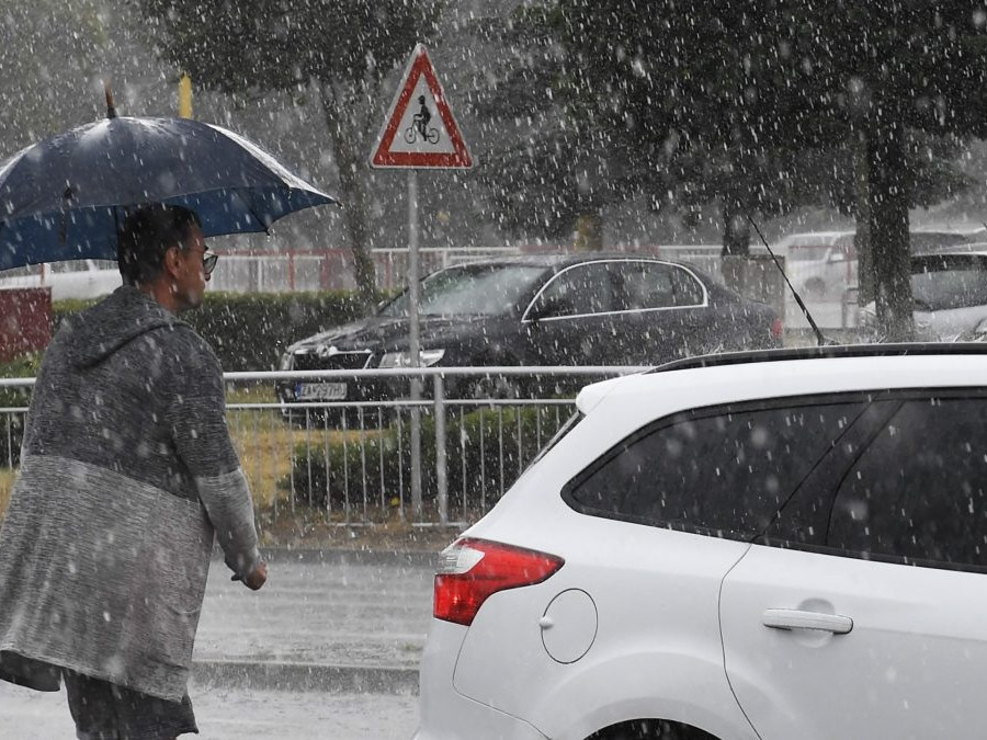 Na snímke prudký lejak, osoba na snímke nad sebou drží dáždnik.