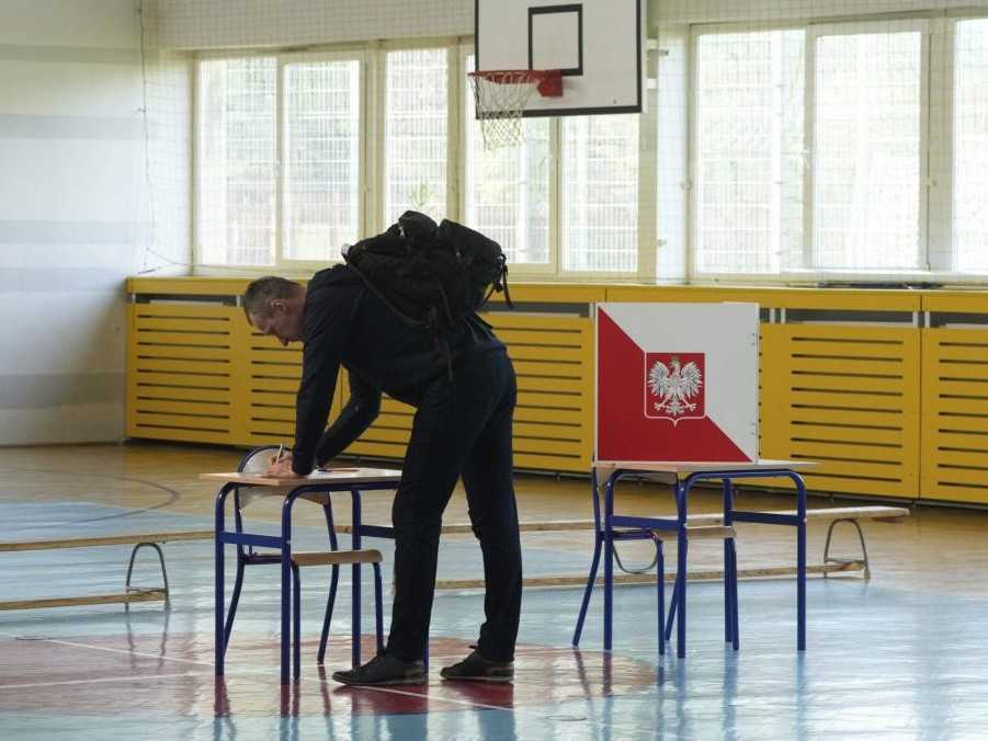 Na snímke volič v Poľsku odovzdáva svoj hlas.