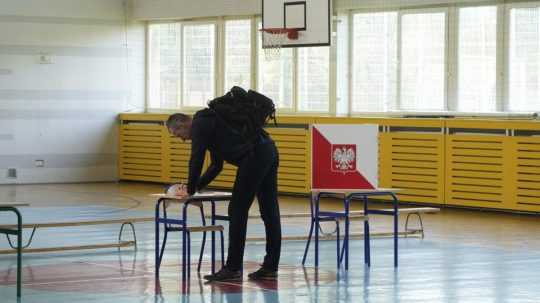 Na snímke volič v Poľsku odovzdáva svoj hlas.