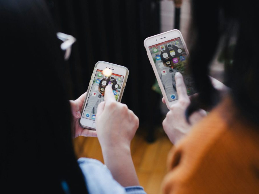 Dve ženy pozerajú na obrazovku smartfónov.