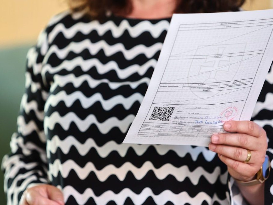 Na ilustračnej snímke učiteľka s vysvedčením v ruke.