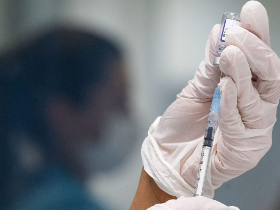 Žena naťahuje z ampulky do injekčnej striekačky vakcínu proti ochoreniu COVID-19.