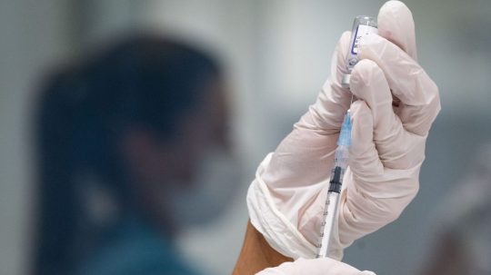 Žena naťahuje z ampulky do injekčnej striekačky vakcínu proti ochoreniu COVID-19.