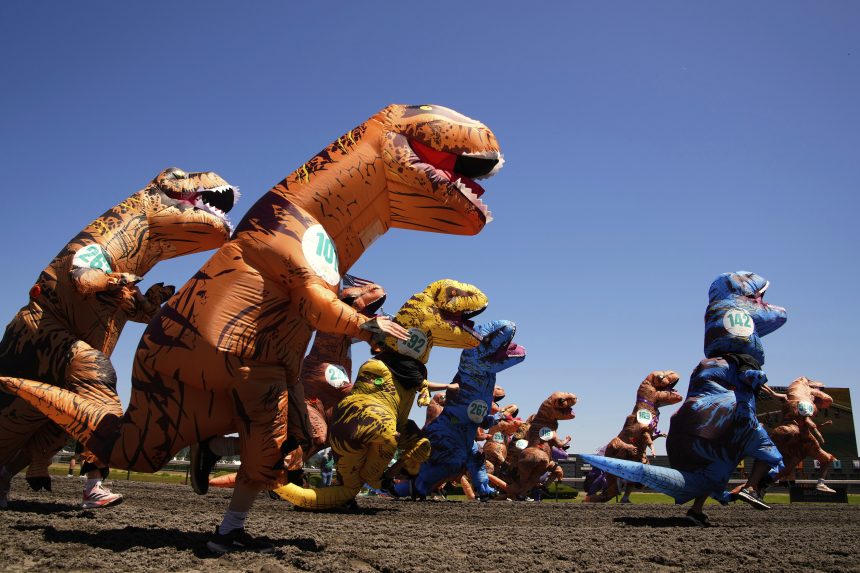 Na snÃƒÂ­mke Ã„Â¾udia pretekajÃƒÂº v kostÃƒÂ½moch T-Rexa.