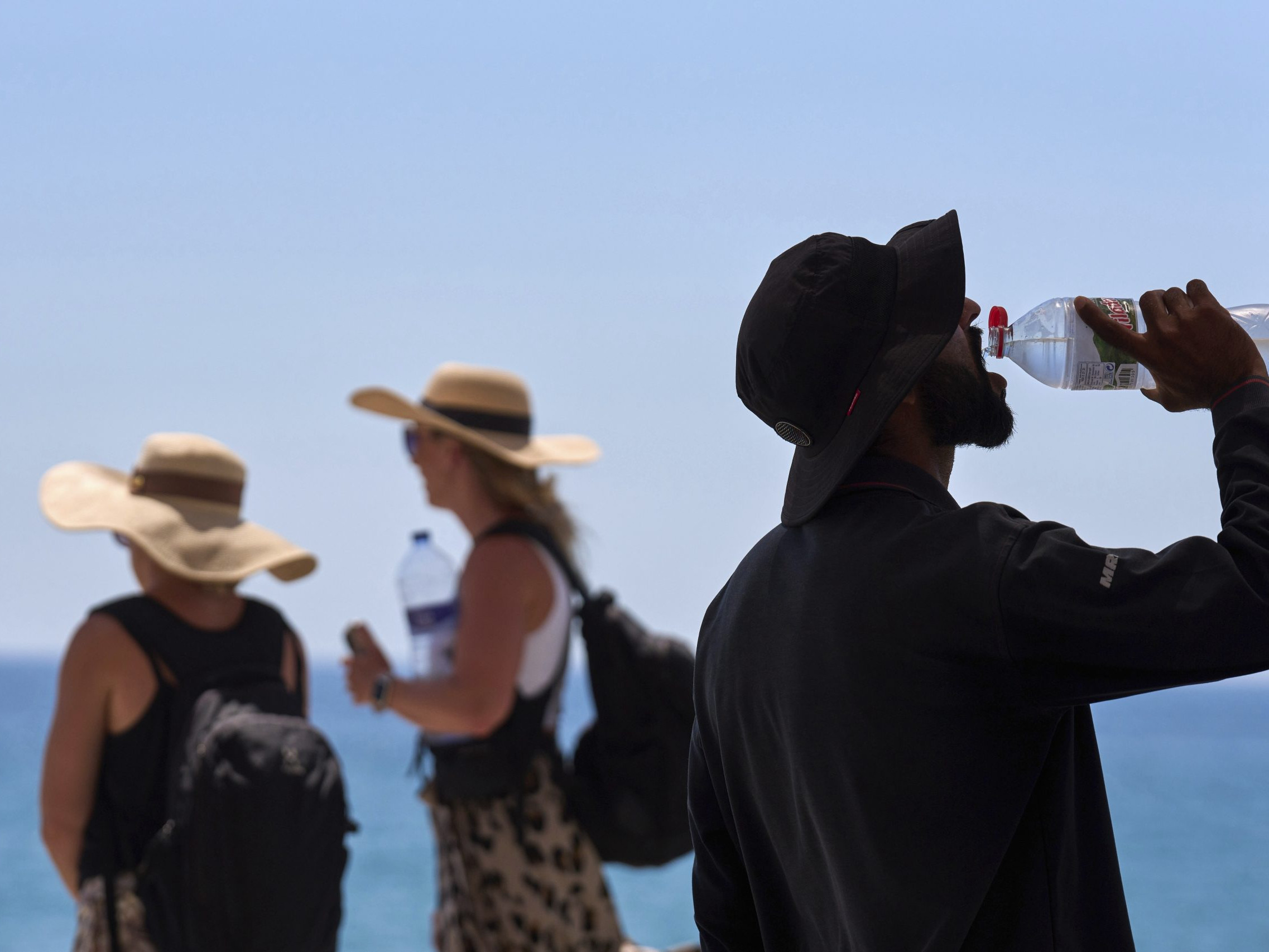 Na archívnej snímke z 2. júla 2025 turista pije vodu počas hrorúčav na pláži v Barcelone.