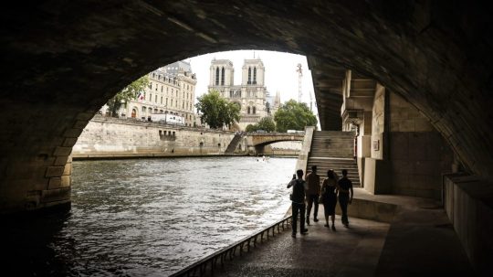 Ľudia sa prechádzajú popri rieke Seina v Paríži.