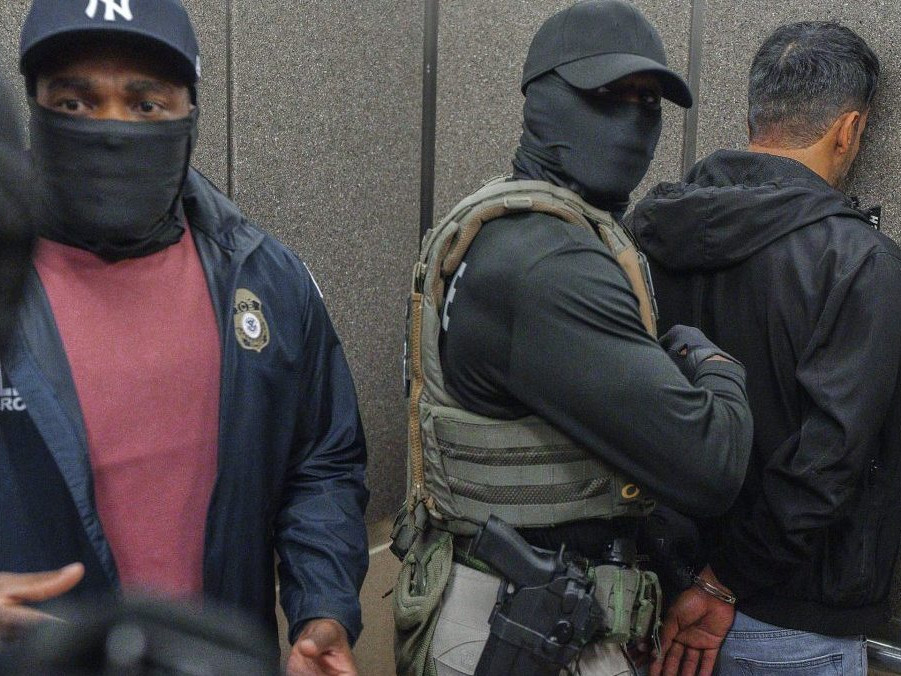 Americkí imigrační úradníci eskortujú zadržaného imigranta.