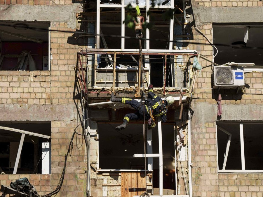 Hasič odpratáva trosky zo zničenej obytnej budovy po nočnom ruskom útoku v Kyjeve.