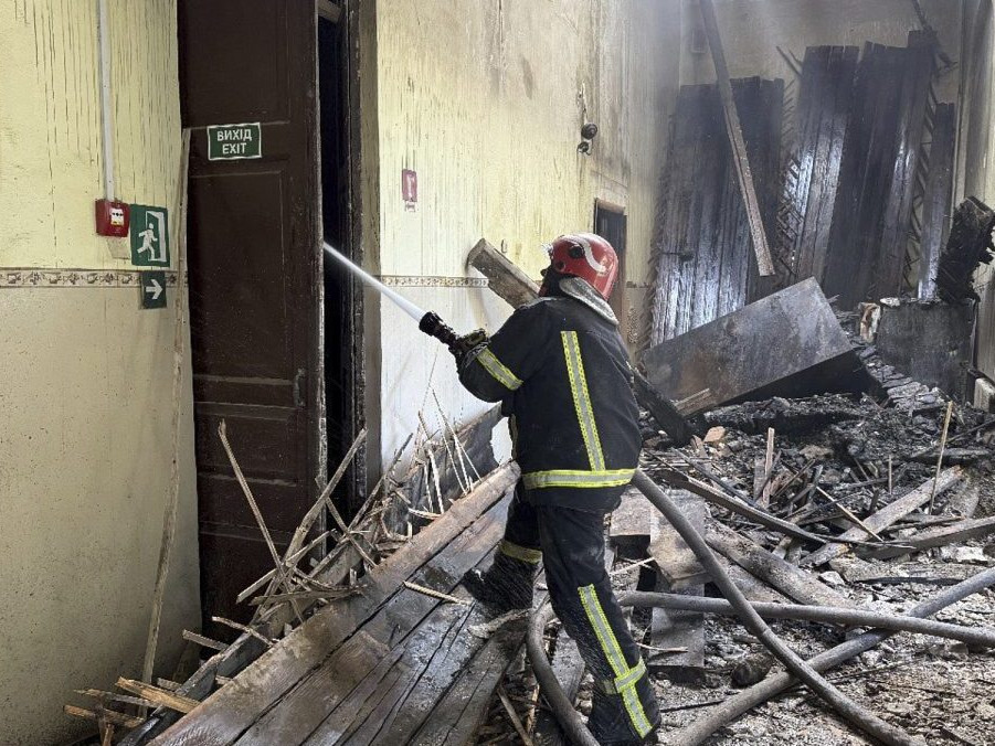 Ukrajinský hasič zasahuje pri požiari školy po ruskom útoku.