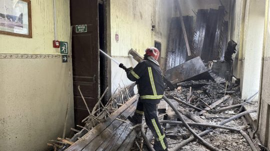 Ukrajinský hasič zasahuje pri požiari školy po ruskom útoku.