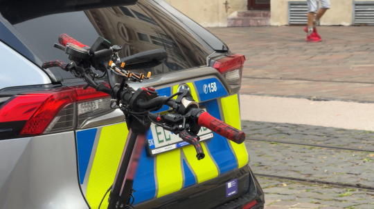 Na snímke kolobežka opretá o policajné auto.