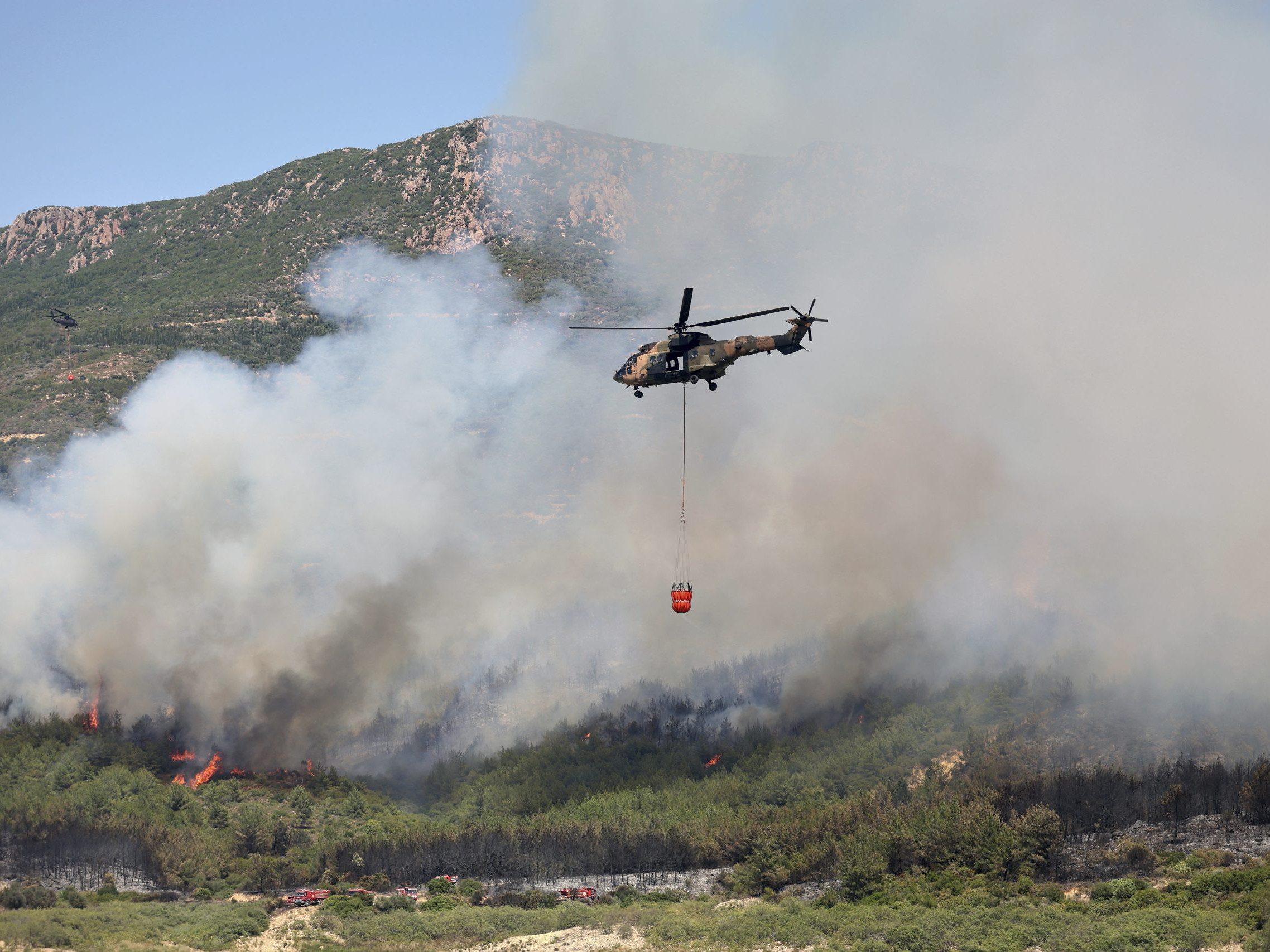 Na snímke vrtuľník zhadzuje vodu počas hasenia lesného požiaru v Seferihisare neďaleko Izmiru na juhozápade Turecka.