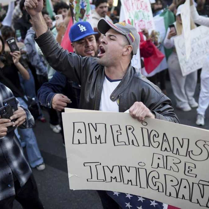 Muž s transparentom "Američania sú imigranti".