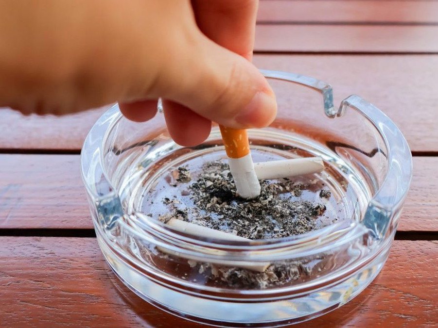 ruka uhasína horiacu cigaretu v popolníku