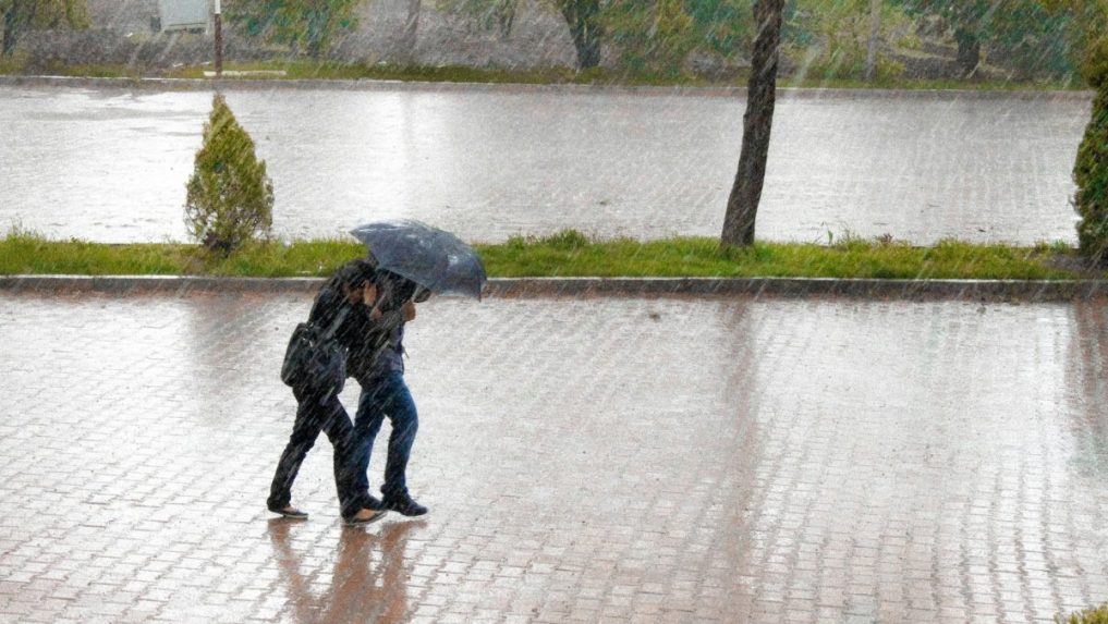 dvaja ľudia s dáždnikom v silnom daždi