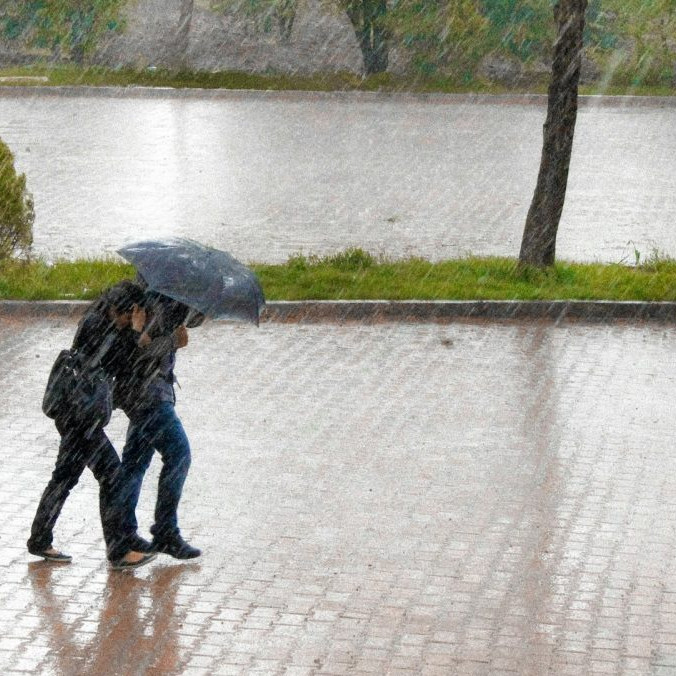 dvaja ľudia s dáždnikom v silnom daždi