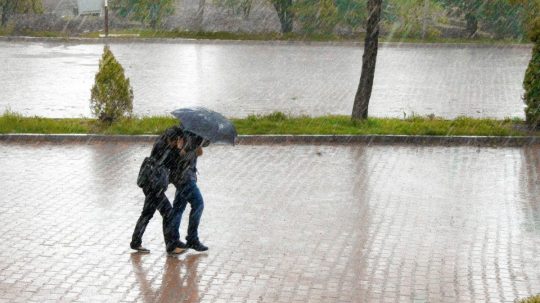 dvaja ľudia s dáždnikom v silnom daždi