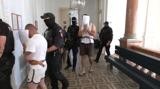 Obvinení s policajnou eskortou na súde.