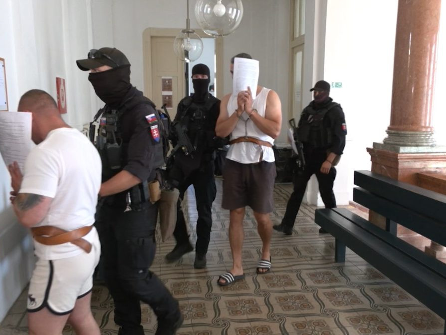 Obvinení s policajnou eskortou na súde.