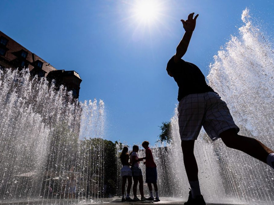 Mladí ľudia sa na priamom slnku chladia vo fontáne.