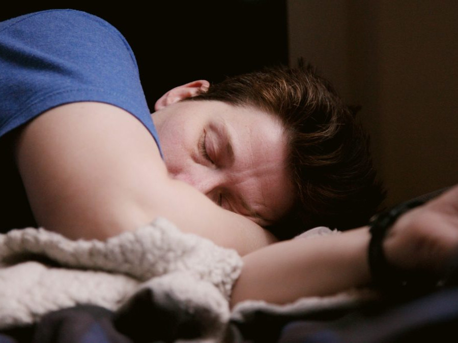 Muž spí v posteli na deke a vankúši.