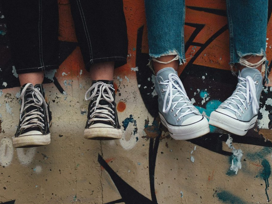 Mladistvé osoby na múre s grafitmi.