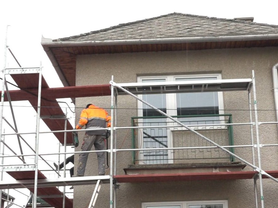 muž na lešení pri rodinnom dome