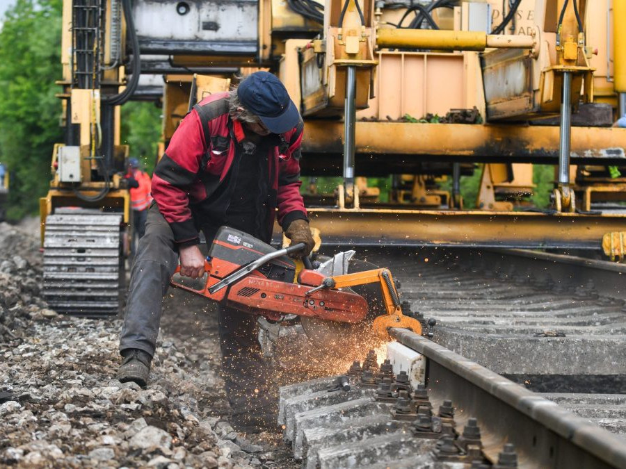 Na snímke traťový robotník reže koľaj a pokladač koľajových polí.