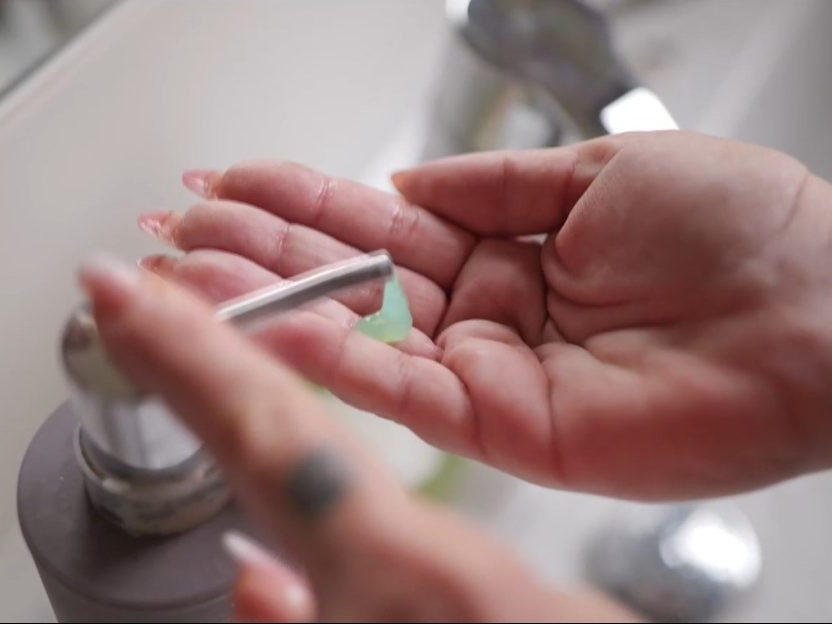 Na snímke žena si dávkuje mydlo do ruky.