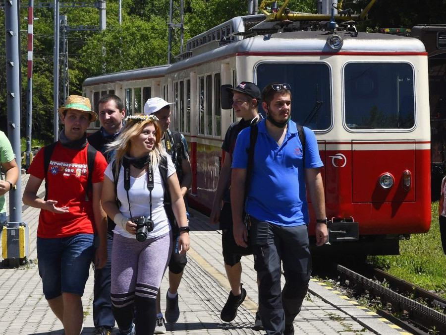Na snímke turisti na peróne na železničnej stanici, za nimi vlak.