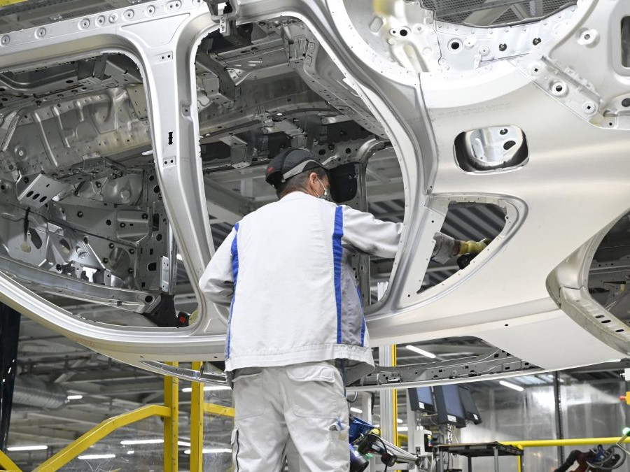 Pracovník v továrni Volkswagen pracuje s rámom vozidla.