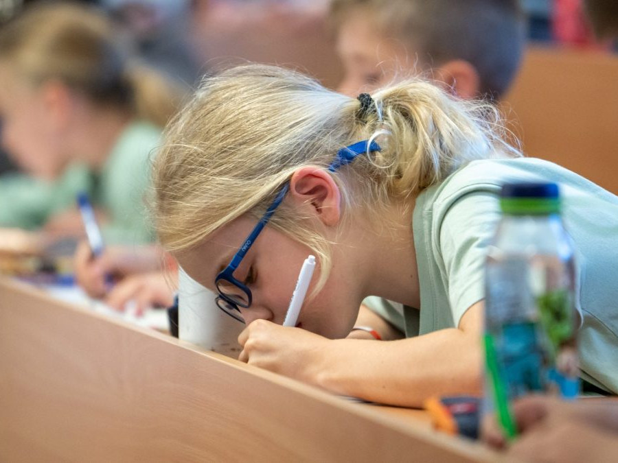 Žiačka píše v lavici.