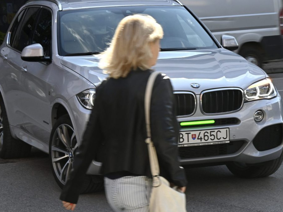 Chodkyňa prechádza pred autom s predným brzdový svetlom.